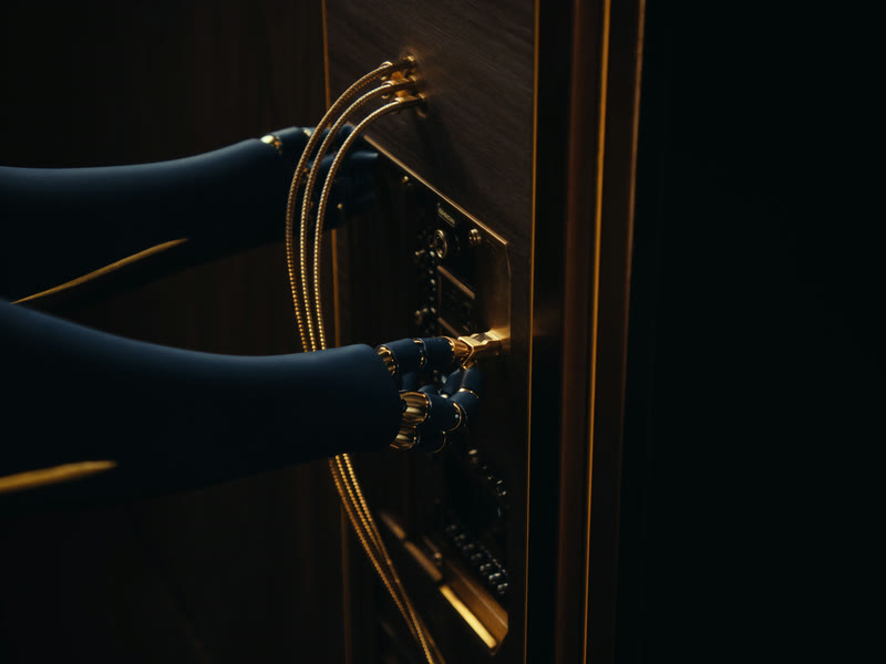 Robot hands connecting brass cables into a panel of ports